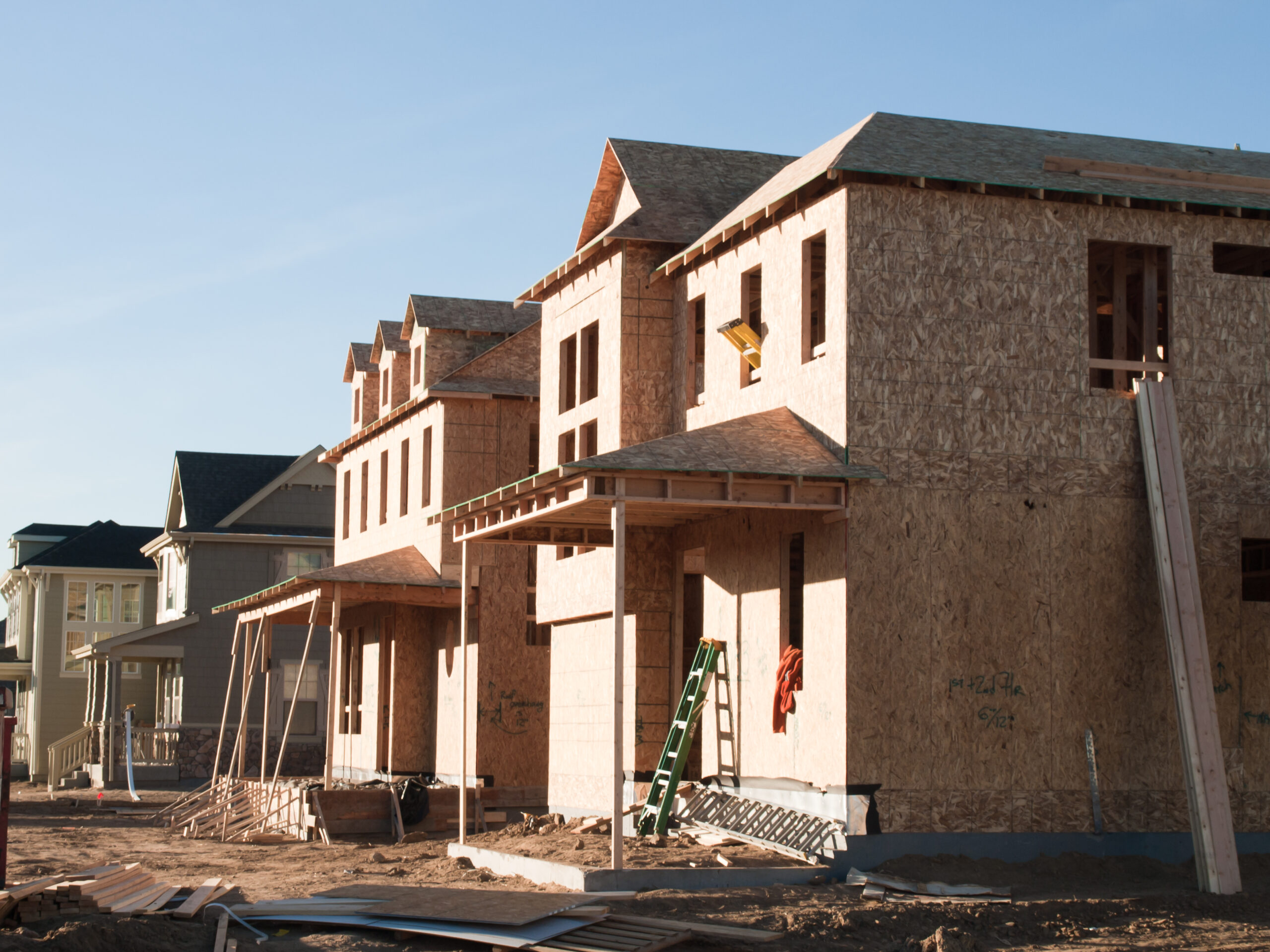 Construction site with partially built wooden houses.