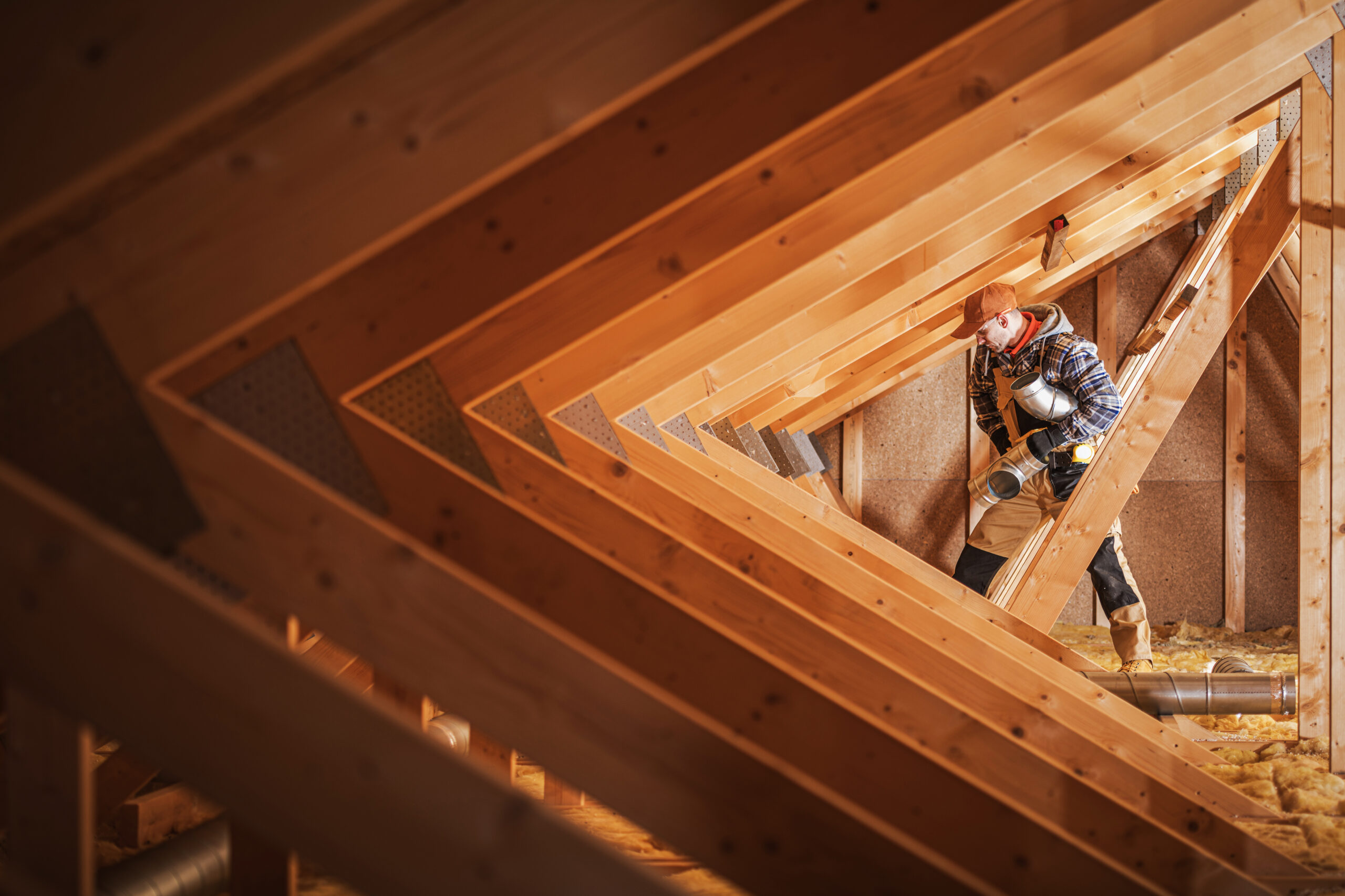 Worker installing materials in a wooden attic.