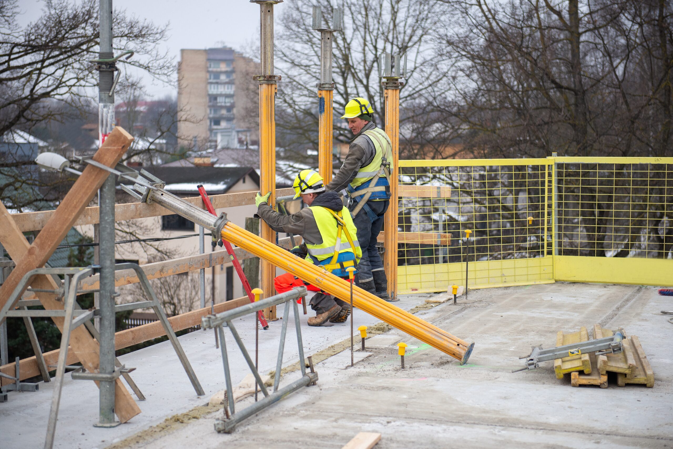 Construction workers installing framework on building site.